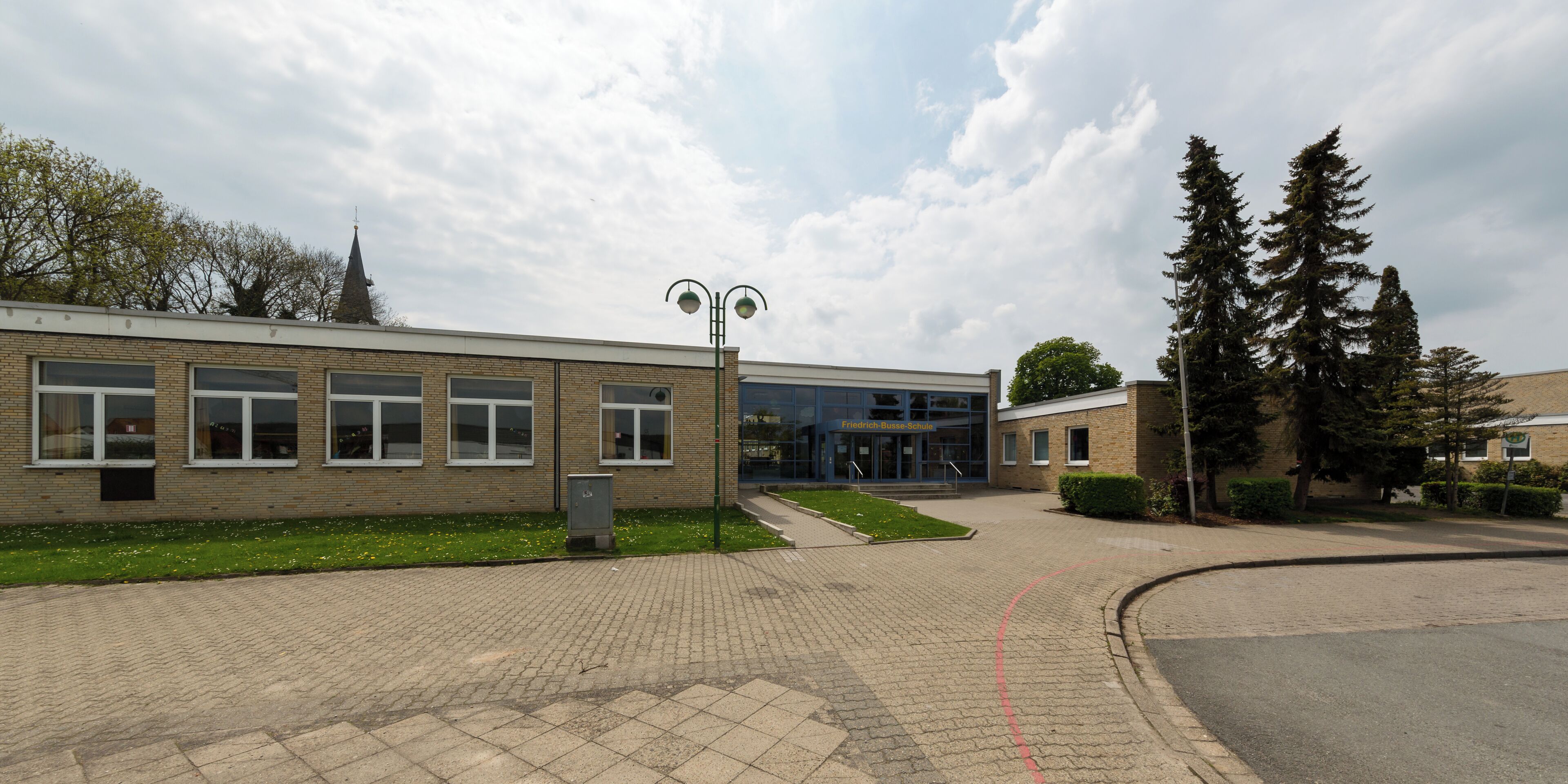 A school building with a brick facade, large windows, and a green lawn.