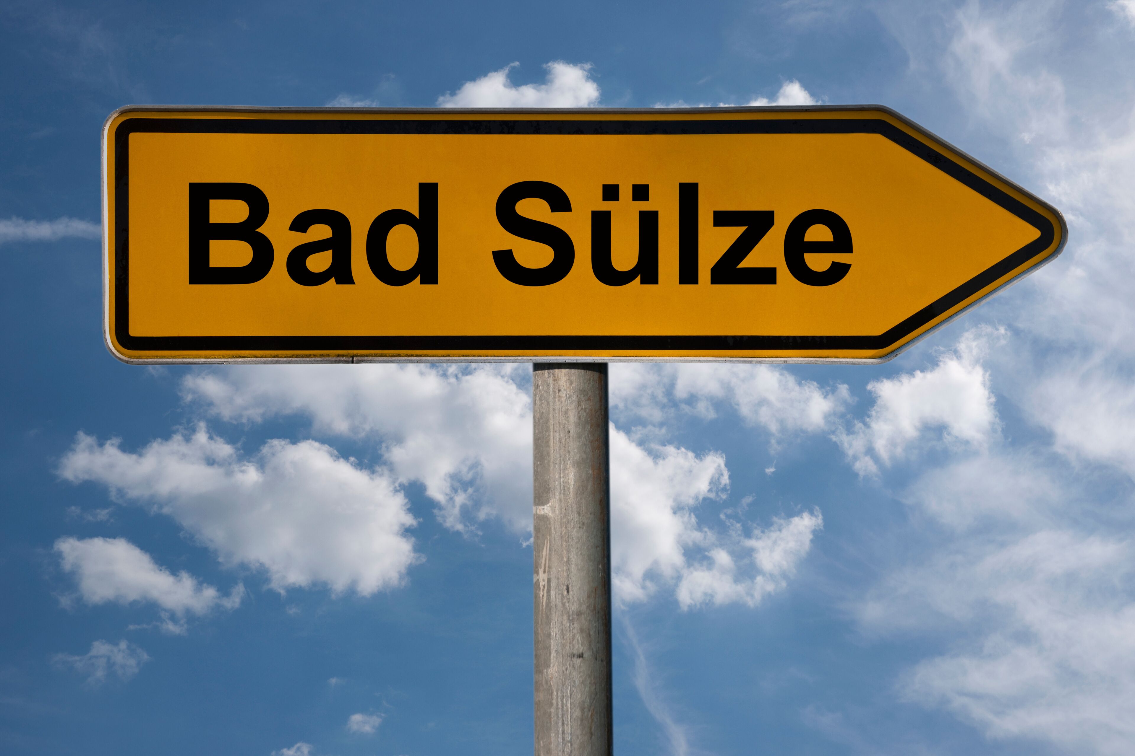 A directional sign with the text "Bad Sulze" against a blue sky with clouds.