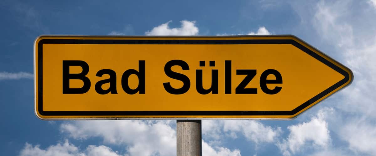 A directional sign with the text "Bad Sulze" against a blue sky with clouds.