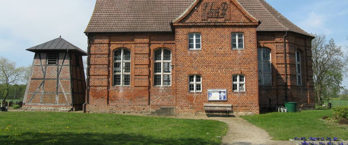 A large brick building with a steeply pitched roof and a small tower.
