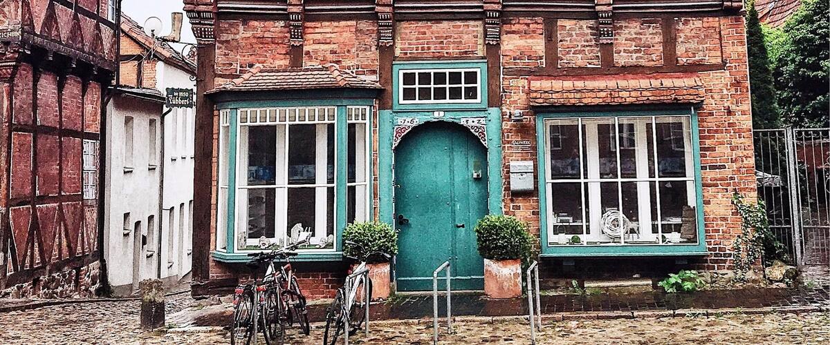 A traditional half-timbered house with a steeply pitched roof, a green door, and a bicycle parked in front.