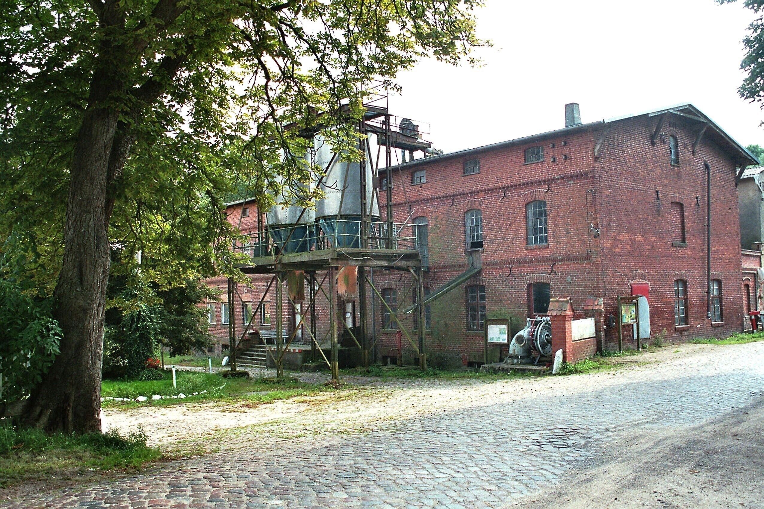 A historic brick building with a metal structure and a cobblestone path.