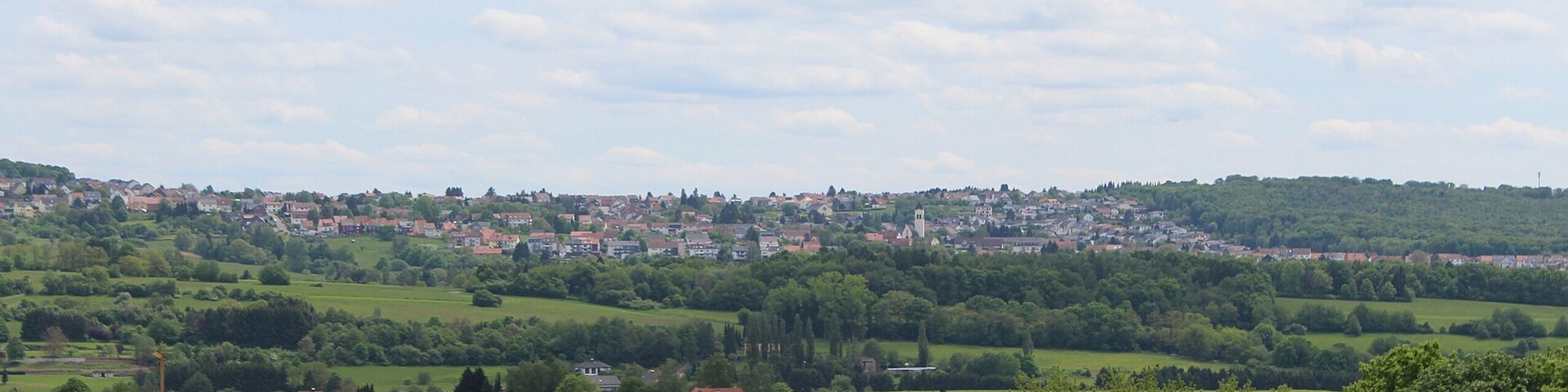 Un paisaje rural con colinas onduladas, un pueblo pequeño y casas dispersas.