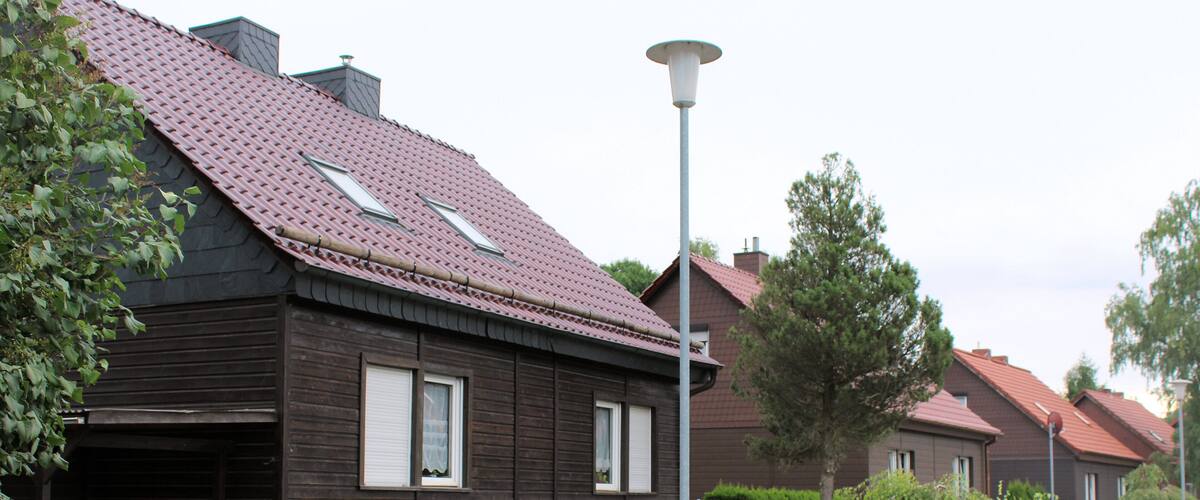 A residential area with houses, a street lamp, and a red car parked in front of a house.
