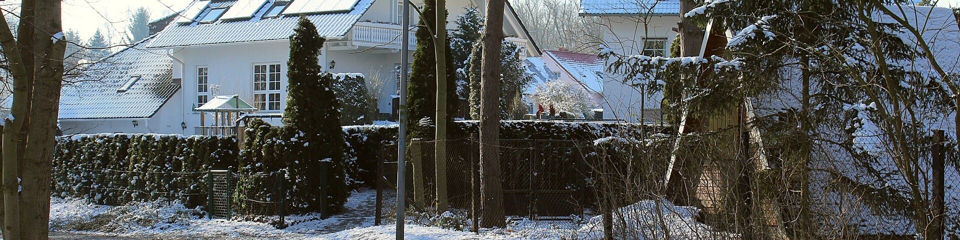 Un barrio residencial cubierto de nieve con casas, árboles y una calle.