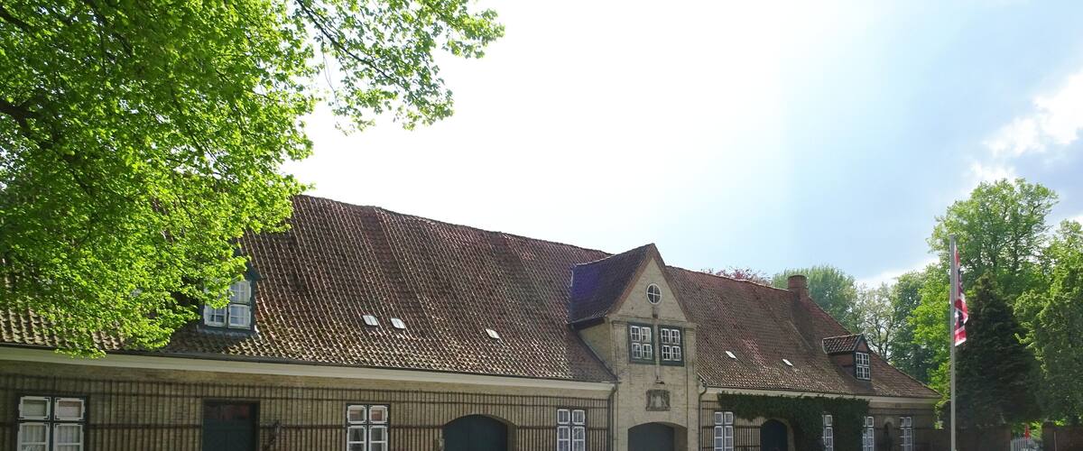 A historic building with a gravel driveway and a flagpole.