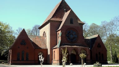En rød murstenskirke med et højt spir og et stort, rundt vindue.