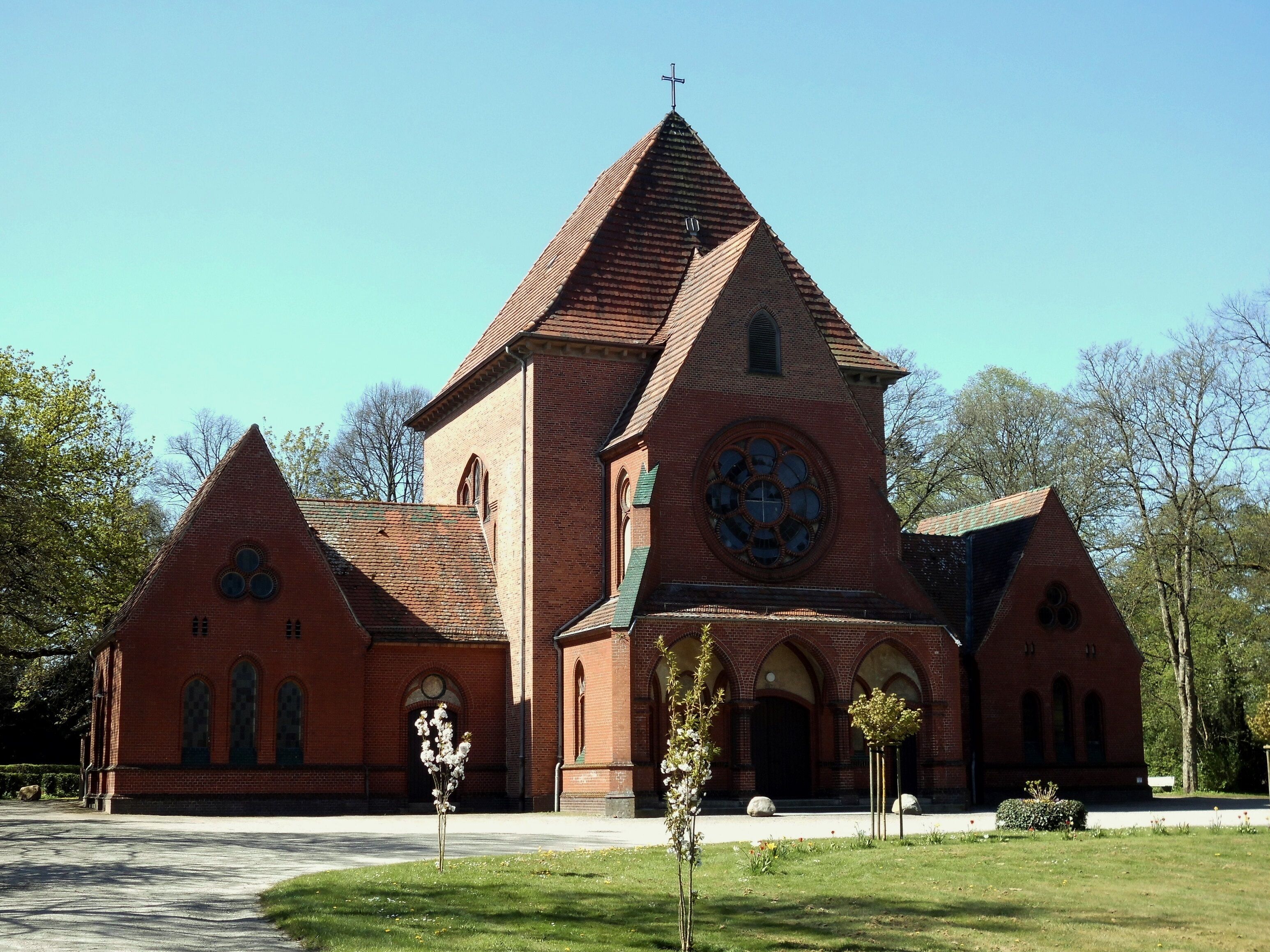 A red brick church with a tall steeple and a large circular window.
