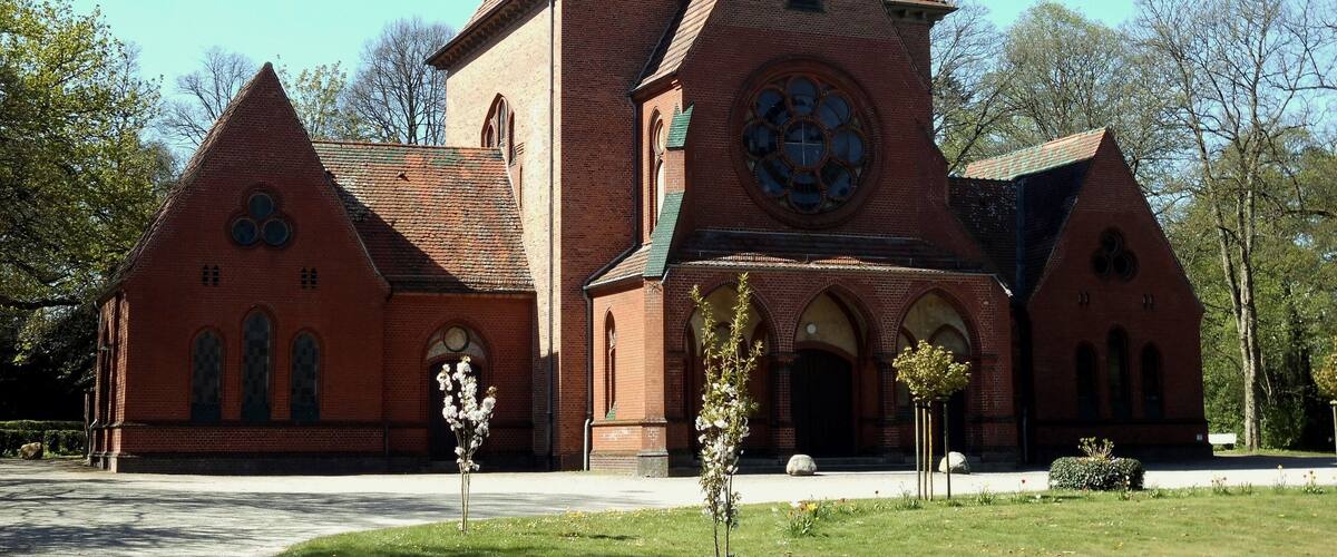 A red brick church with a tall steeple and a large circular window.