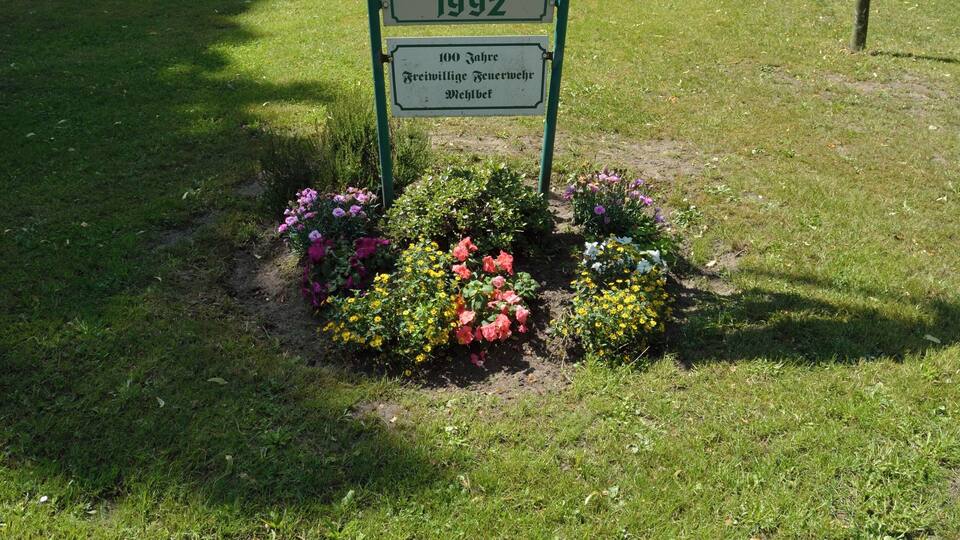 A signpost with the text 'Schönees Dorf' and years '1988' and '1992' along with a message in German.