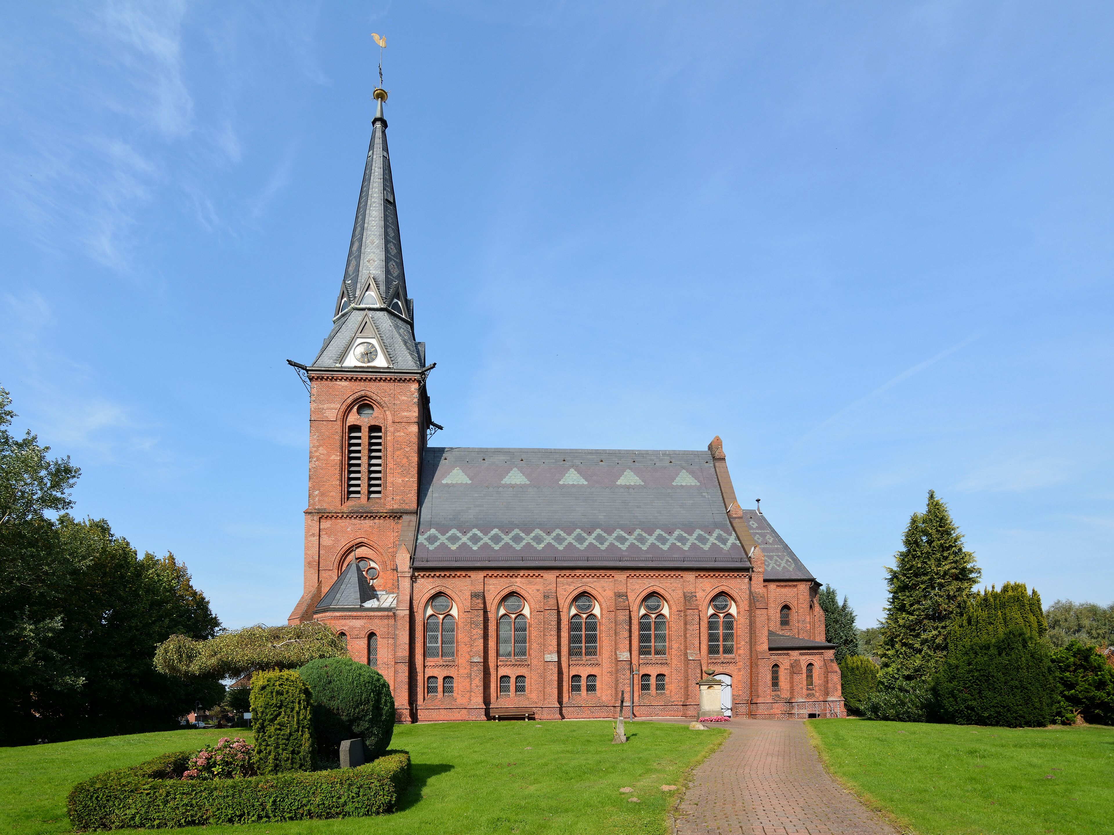 A large brick church with a tall steeple and a clock.