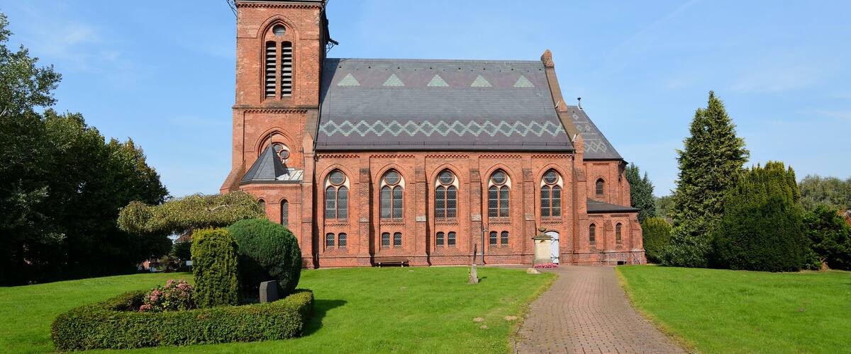 A large brick church with a tall steeple and a clock.