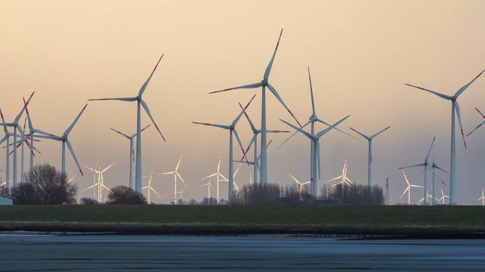 A wind farm with multiple wind turbines against a dusky sky.
