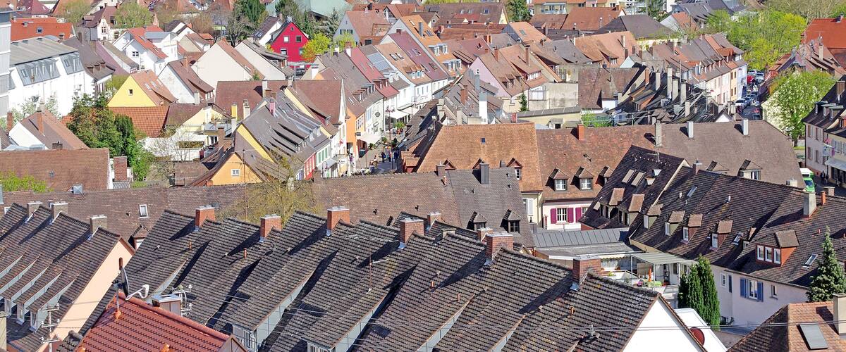 A densely packed town with a variety of traditional European architecture, including red-roofed houses and a prominent yellow building.