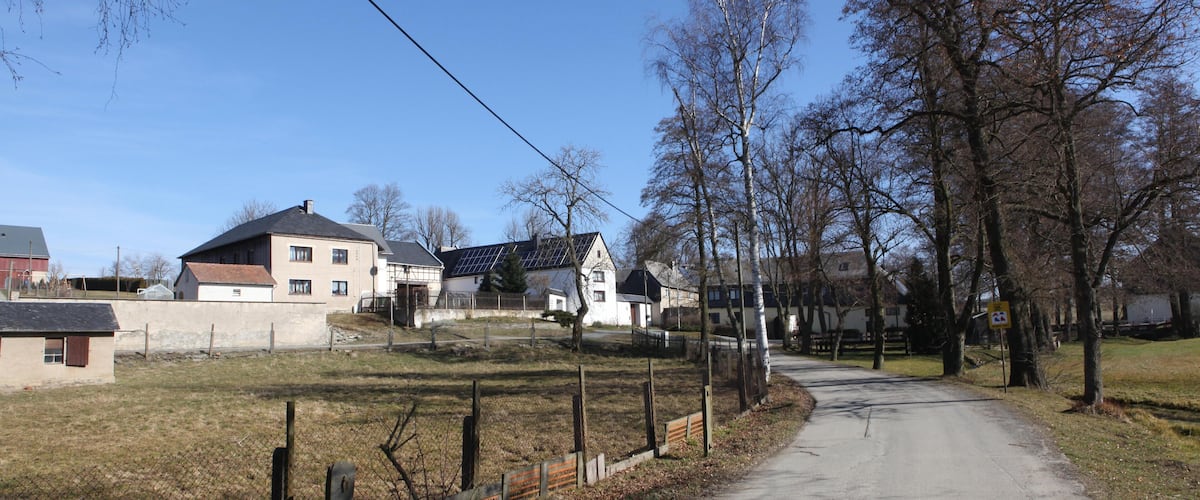 A rural road with houses and trees.