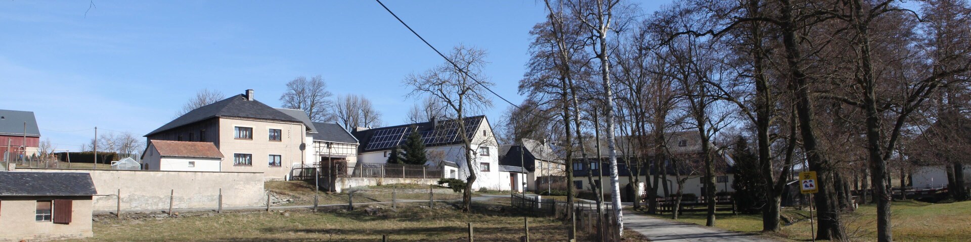 A rural road with houses and trees.