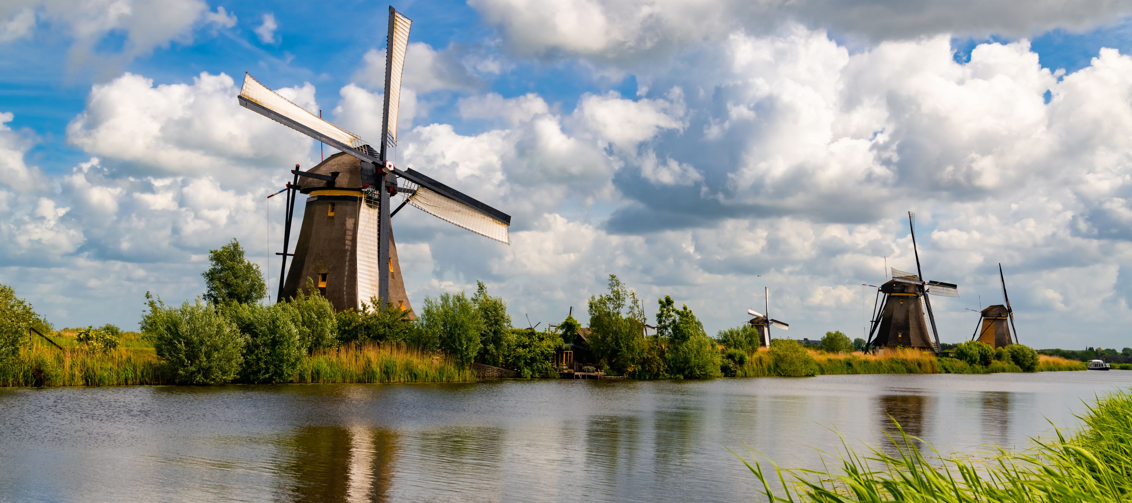 A river with windmills and a boat.