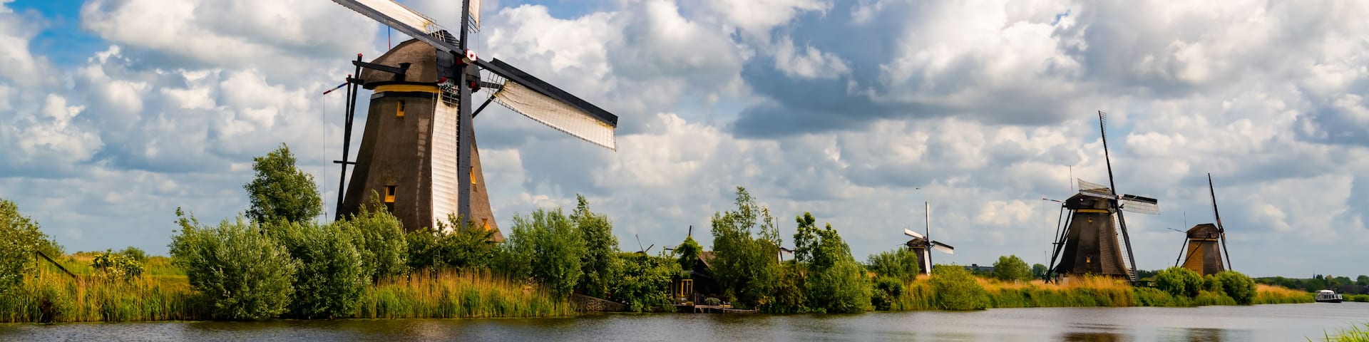A river with windmills and a boat.