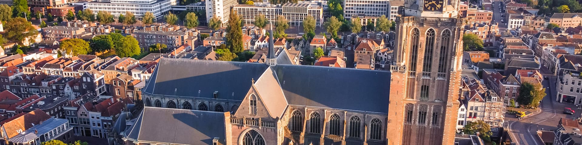 A historic church with Gothic architecture, surrounded by a dense urban area with modern buildings and a river.