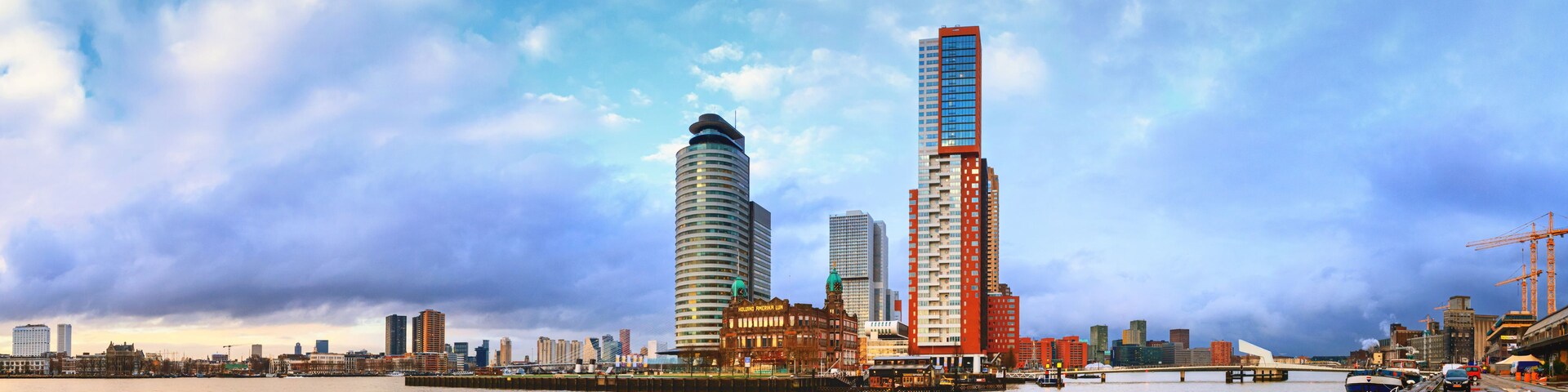 Un horizonte urbano con un edificio curvo destacado y un rascacielos imponente.