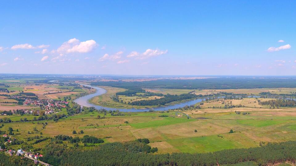 A river winding through a valley with scattered houses and dense forests.