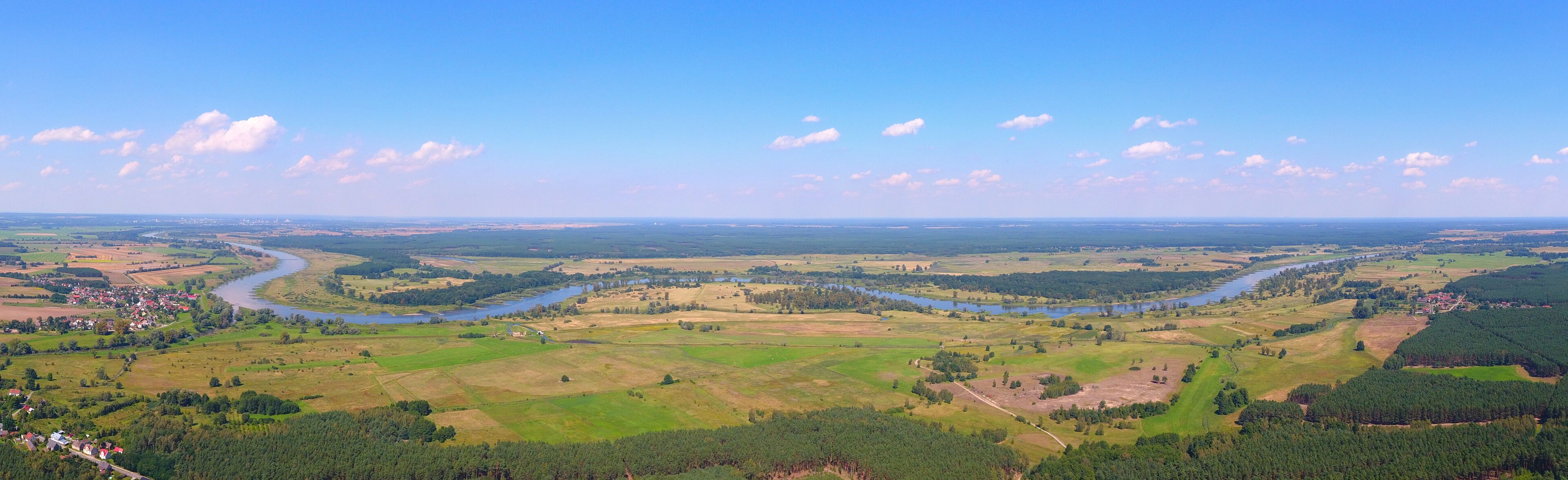 A river winding through a valley with scattered houses and dense forests.