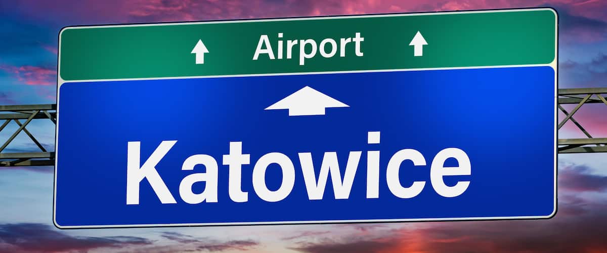 A highway sign with 'Airport' and 'Katowice' written on it.
