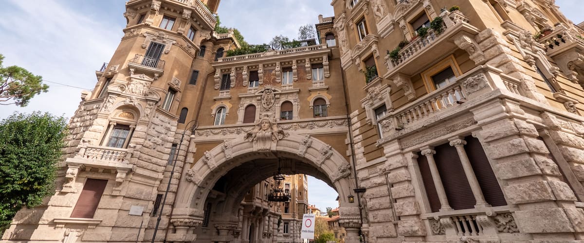 A historic stone archway with intricate carvings and a tall tower.