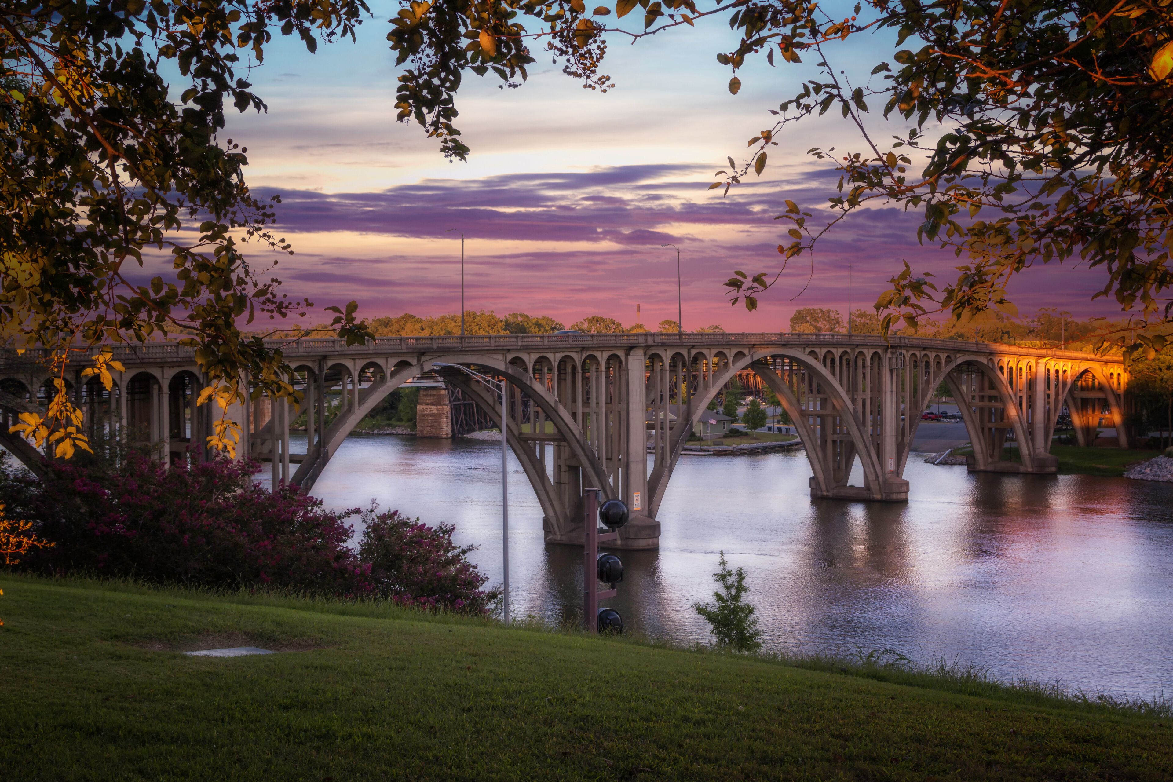 A stone bridge over a river at dusk with a sunset sky.