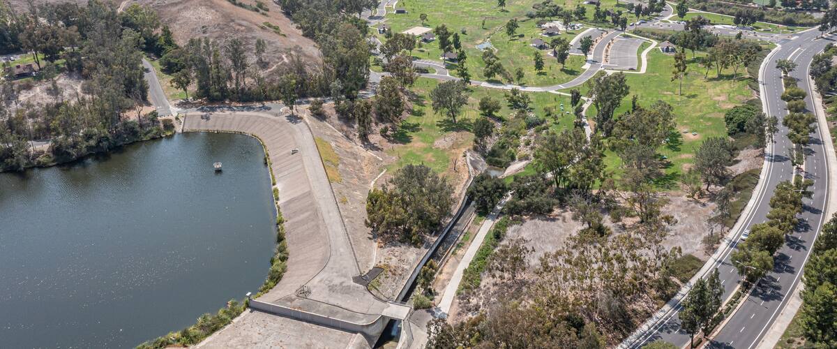 A river, a dam, a highway, and a park with trees and grass.
