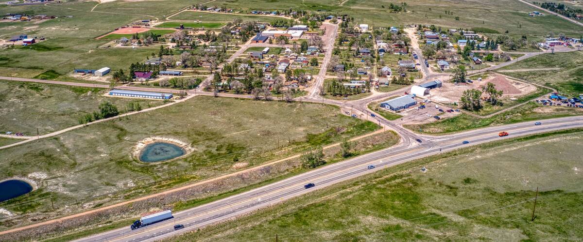 An aerial view of a small town with a main road, a roundabout, and a large body of water.