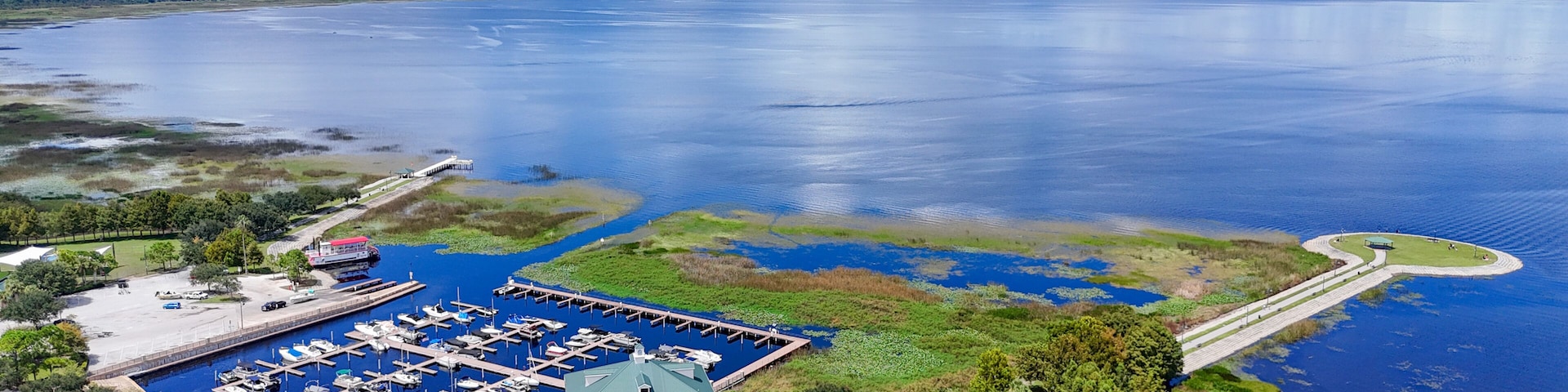 A marina with boats, a large body of water, and a bridge connecting to the mainland.