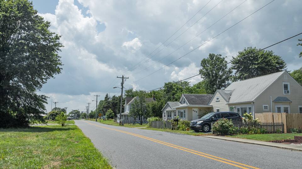 A suburban street lined with houses, a clear sky, and power lines.