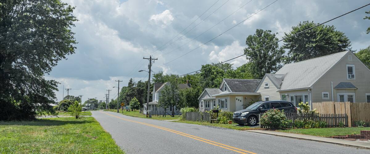 A suburban street lined with houses, a clear sky, and power lines.