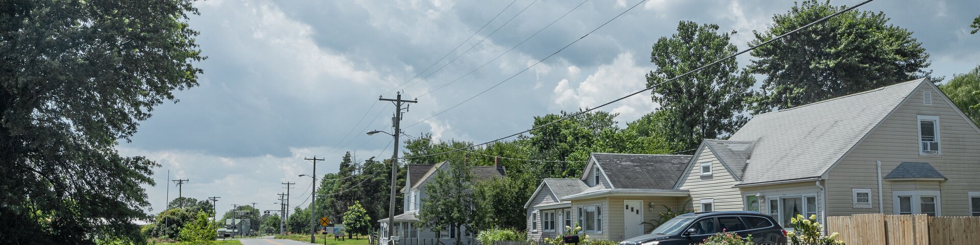 A suburban street lined with houses, a clear sky, and power lines.