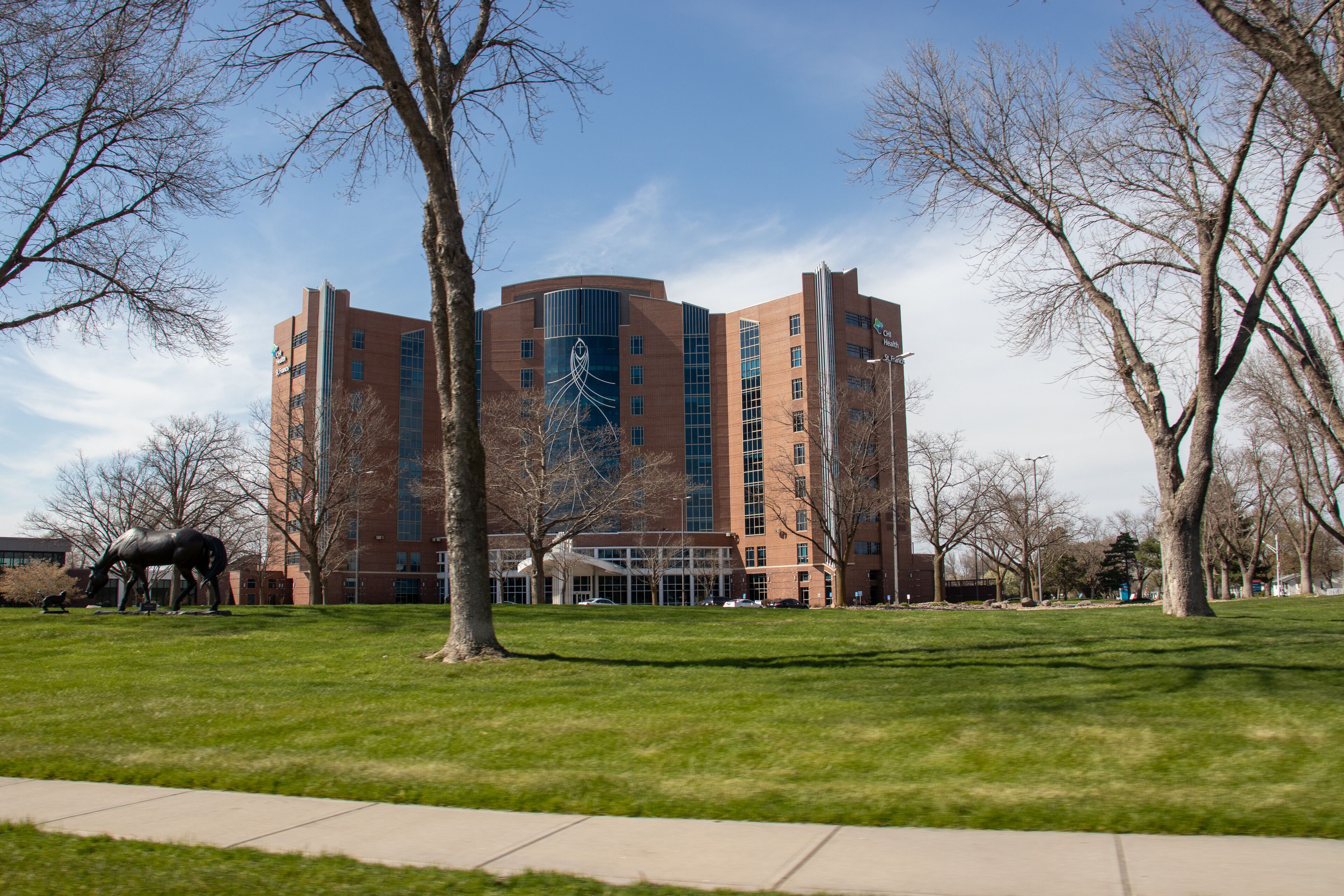 A large brick building with a modern design, surrounded by a grassy area and leafless trees.