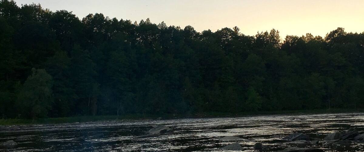 A campfire by a river at dusk.