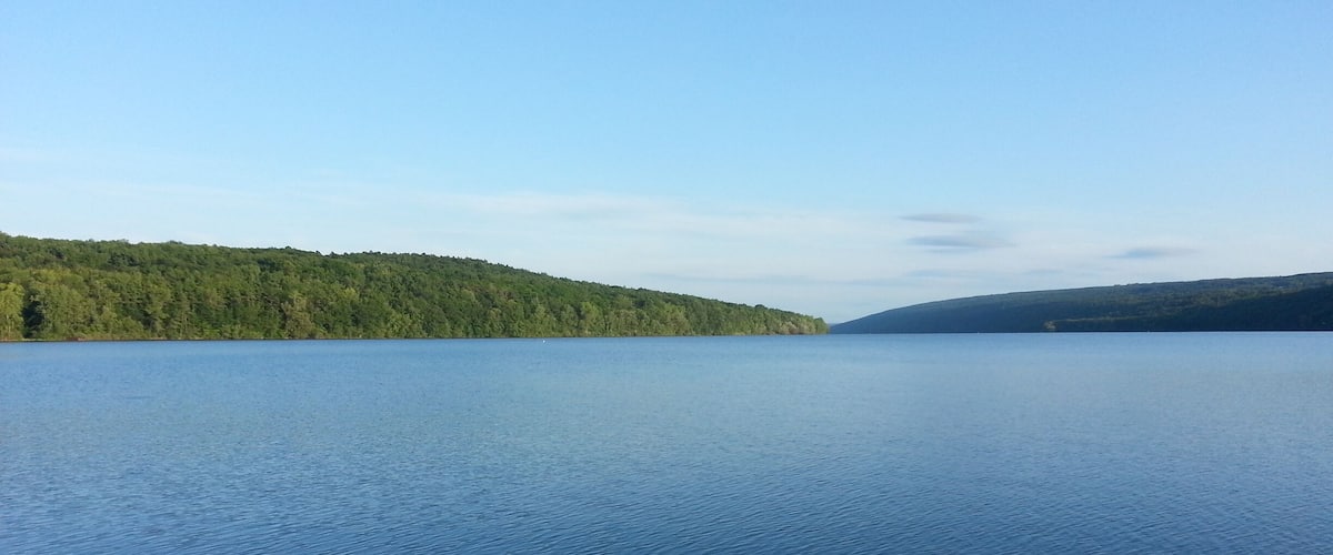 A calm lake surrounded by forested hills.