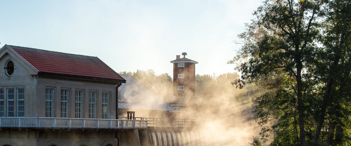 Countryside views and old watermill buildings in a misty sunrise