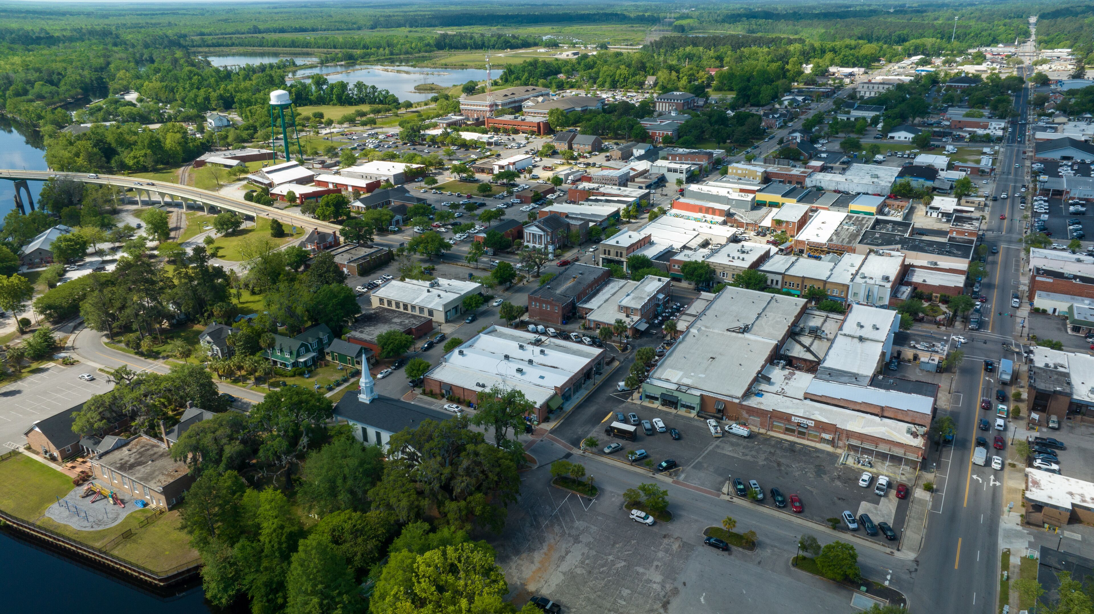 An aerial view of a town with a river, a bridge, and various buildings.