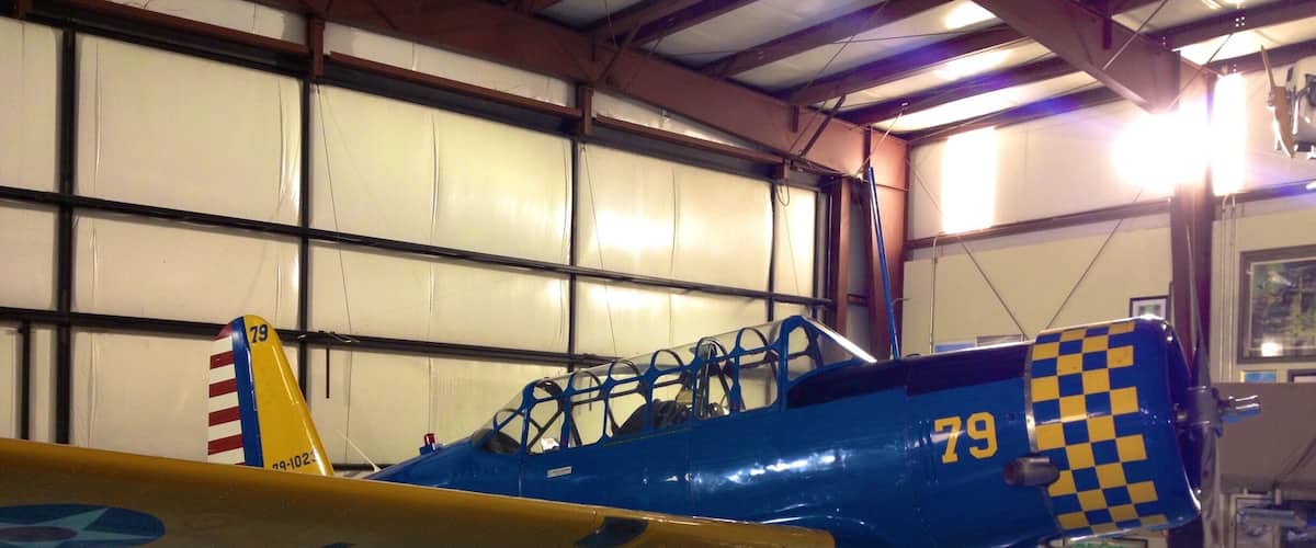 A vintage blue and yellow biplane with the number 79 in a hangar.