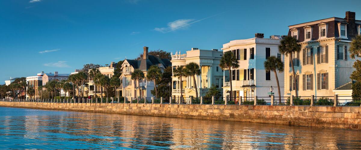 A waterfront with historic buildings and palm trees.