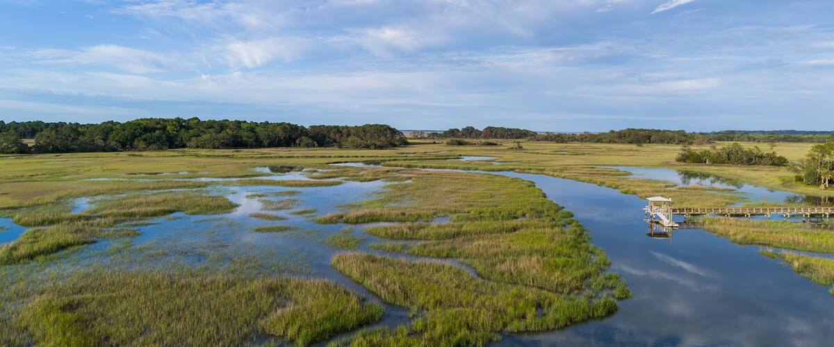 A river meandering through a marshland with a boat docked on the right.