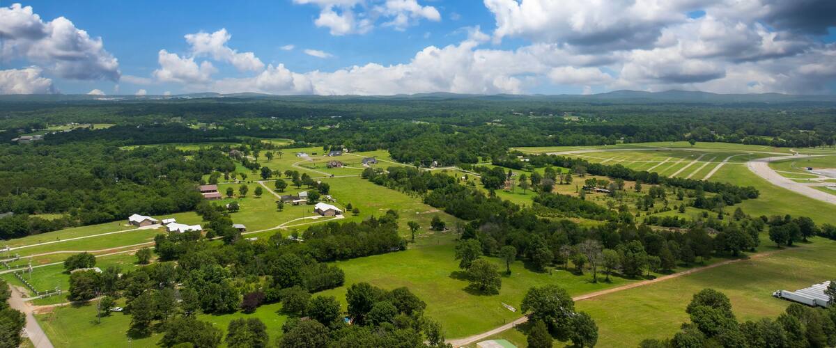 A lush green landscape with rolling hills, scattered trees, and a few buildings.