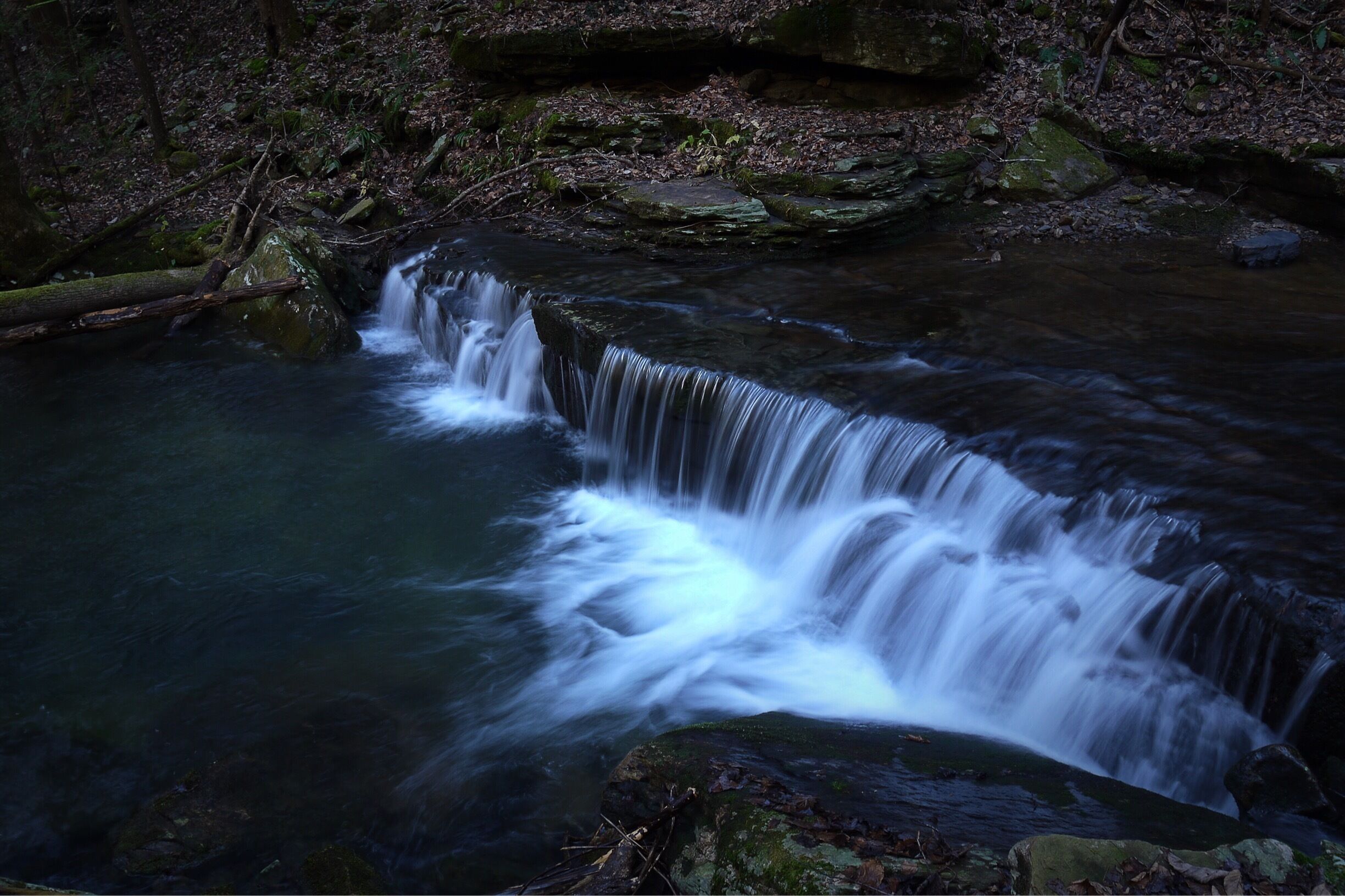 A waterfall in a forested area with rocks and trees.