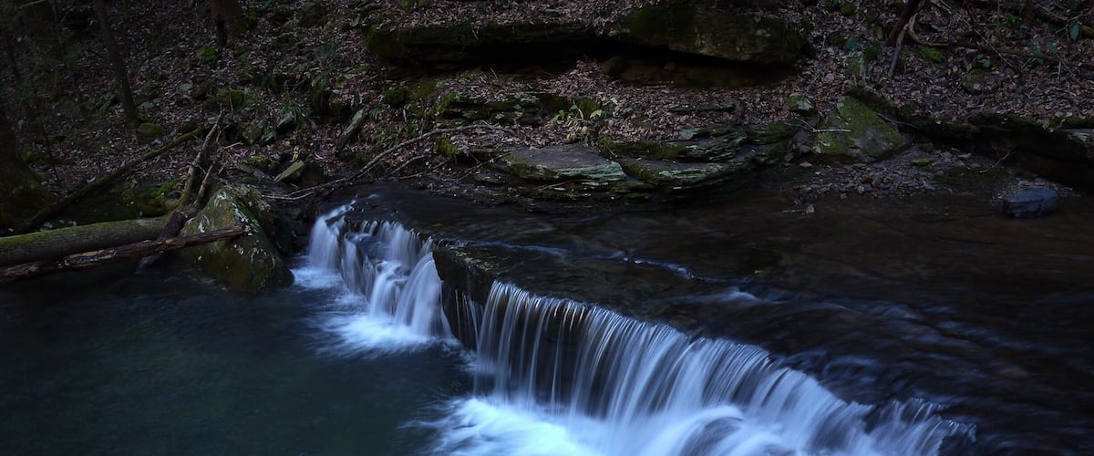 A waterfall in a forested area with rocks and trees.