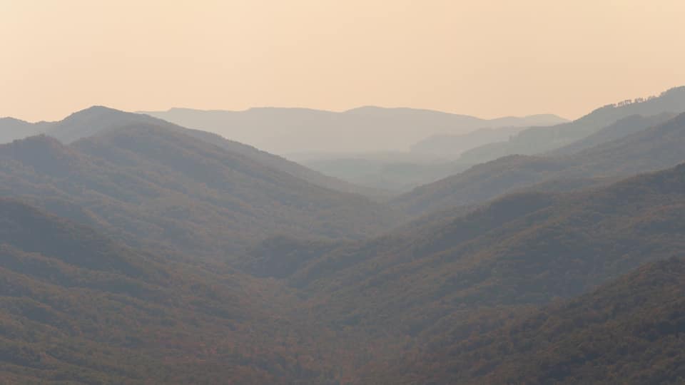 A valley with rolling hills and distant mountains.