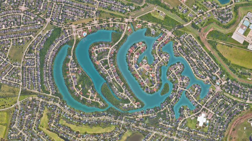 An aerial view of a residential area with winding water bodies and interconnected roads.