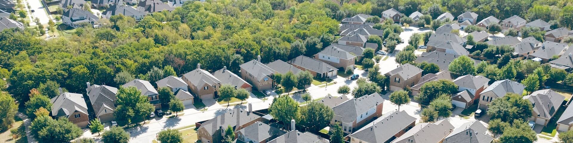A residential area with houses, trees, and a clear sky.