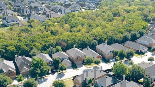 Panorama aerial view green lush trees surrounding two-story suburban houses with small backyard, well-trimmed landscape, large residential street in Bartonville and Argyle, Denton County, Texas
